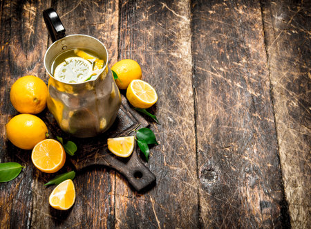 Fresh lemonade in a jug with slices of lemon . On wooden background.の写真素材