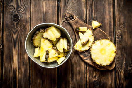 Slices of pineapple in a pot. On a wooden table.の写真素材