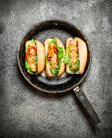 Street food. Hot dogs with herbs and vegetables in the pan.On rustic background.の写真素材