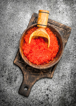 red caviar in a wooden bowl with a shovel. On rustic background .の写真素材
