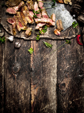 Meat grill. Sliced grilled pork with an old hatchet ,spices and herbs .On the old wooden table.の写真素材