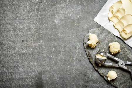 Balls of butter with a measuring scissors. On the stone table.の写真素材