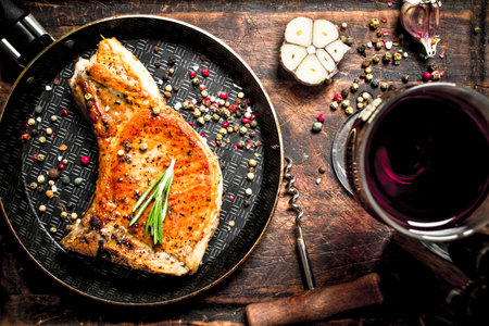 Grilled pork steak with red wine. On wooden background.の写真素材