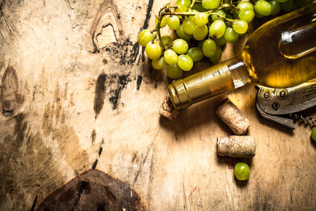 White wine with a bunch of grapes. On wooden background.の写真素材
