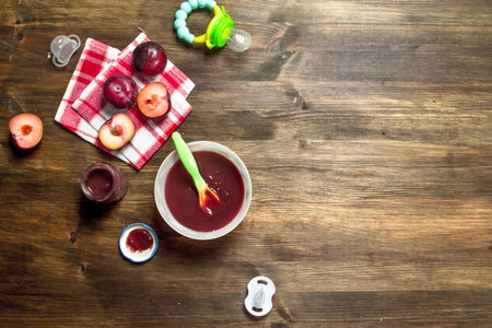 Baby food. Baby puree from fresh plums. On a wooden background.の写真素材