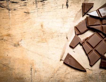 Broken chocolate bar. On a wooden background.の写真素材
