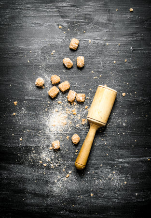 Brown cane sugar with pestle. On black rustic background.の写真素材