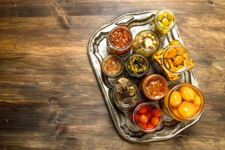 Preserved mushrooms and vegetables on a steel tray. On a wooden table.の写真素材