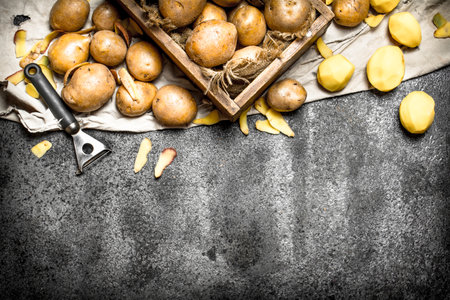 The peeled potatoes with an old wooden box. On rustic background.の写真素材