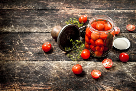 Pickled tomatoes with herbs spices and seamer. On a wooden background.の写真素材