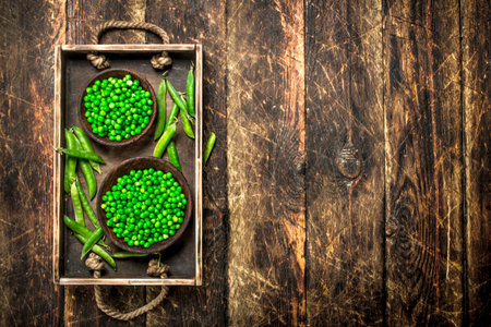 Fresh green peas in a bowl. On a wooden background.の写真素材