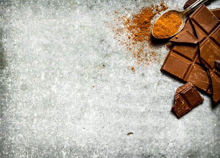 Chocolate with cocoa powder in the spoon. On the stone table.の写真素材