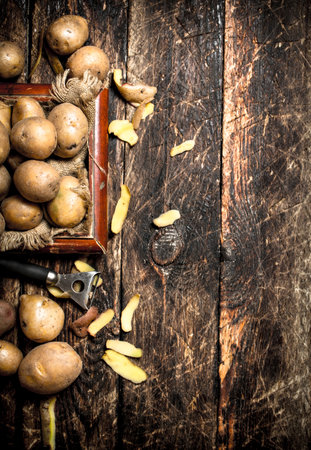 Fresh potatoes in an old wooden tray. On wooden background.の写真素材