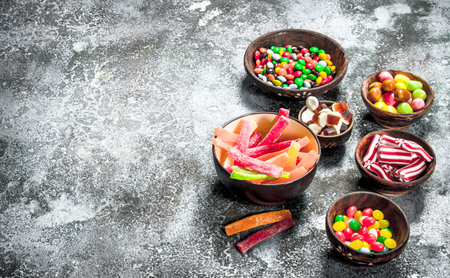 Multicolored candy, jelly and marshmallows in a bowl. On a rustic background.