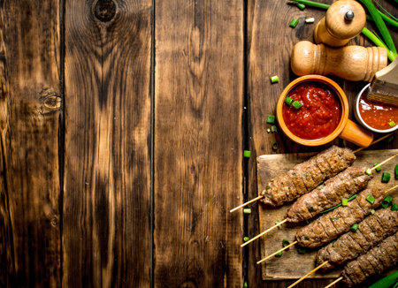 Kebab with green onions and hot sauce. On a wooden table.の写真素材