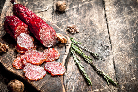 salami with herbs and spices on a board. On a wooden background.の写真素材