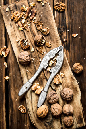 Walnuts with Nutcracker on the Board. On a wooden table.の写真素材