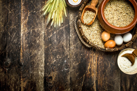 Flour with wheat grains on an old tray. On a wooden background.の写真素材