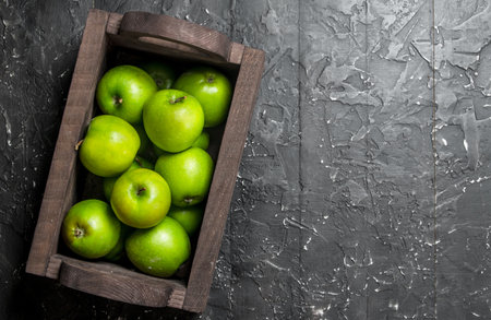 Green apples in a wooden box. On a dark wooden background.の写真素材