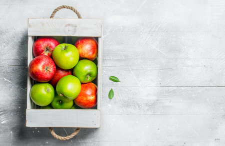 Juicy fresh green and red apples in a wooden box.On white rustic background.の写真素材