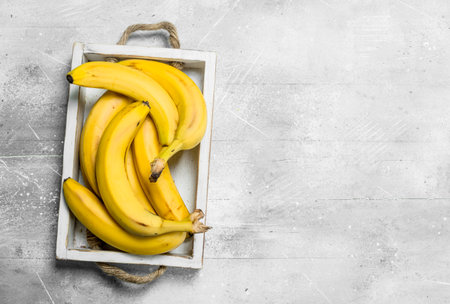 Fresh bananas in a wooden box. On white rustic background.の写真素材