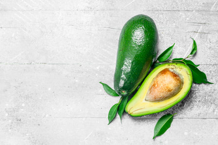 Ripe avocado with leaves. On white rustic background.の写真素材
