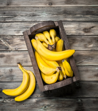 Lots of bananas in a black wooden box. On a black wooden background.の写真素材