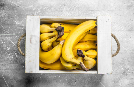 Fresh bananas in a wooden box. On white rustic background.の写真素材