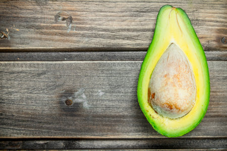 One ripe avocado cut with bone. On a dark wooden background.