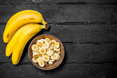 Juicy fresh bananas and banana slices in a plate. On rustic background.の写真素材