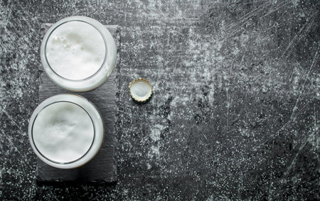 Two glasses of beer and cover. On dark rustic backgroundの写真素材