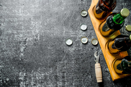 Beer bottles on a stand and opener. On black rustic backgroundの写真素材