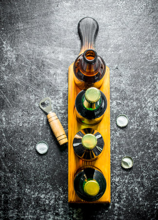 Beer bottles on a stand and opener. On black rustic backgroundの写真素材