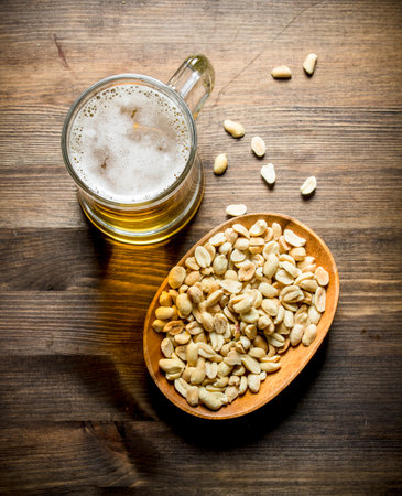 Beer and peanuts in the bowl. On wooden backgroundの写真素材