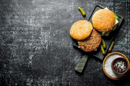 Burgers on the cutting board and spices in the bowl. On rustic backgroundの写真素材
