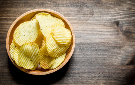 Chips in wooden bowl. On wooden backgroundの写真素材