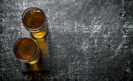 Two glasses of beer. On black rustic background