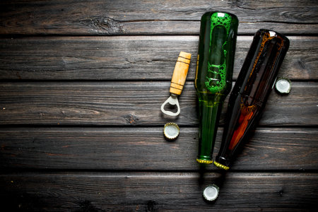Beer in glass bottles and opener. On wooden backgroundの写真素材