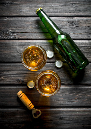 Glasses with beer bottle. On black wooden backgroundの写真素材