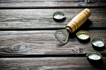 Opener with covers from beer bottles. On black wooden backgroundの写真素材