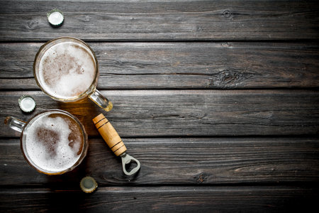 Beer mugs and opener. On wooden backgroundの写真素材