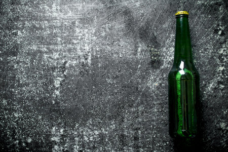 One closed glass bottle of beer. On black rustic backgroundの写真素材