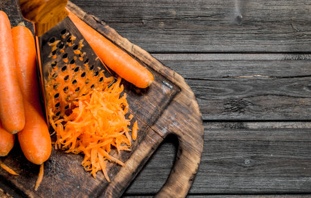 Grated carrots on a cutting board with a grate. On wooden backgroundの写真素材