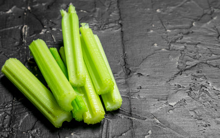 Pieces of fresh celery. On black rustic backgroundの写真素材