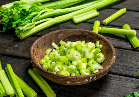 Pieces of celery in a wooden bowl. On black wooden backgroundの写真素材