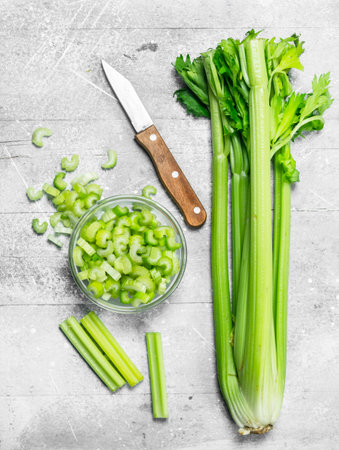 Sliced celery in a bowl with a knife. On rustic backgroundの写真素材