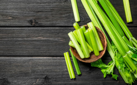Pieces of celery in a wooden bowl. On black wooden backgroundの写真素材