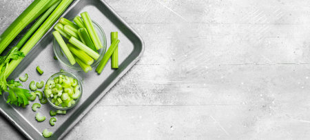 Pieces of celery in a bowl on a tray. On white rustic background