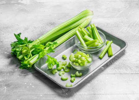Pieces of celery in a bowl on a tray. On white rustic backgroundの写真素材