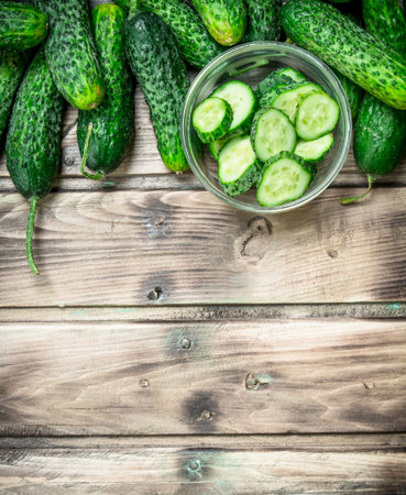 Cucumbers and cucumber slices in a glass bowl. On wooden backgroundの写真素材